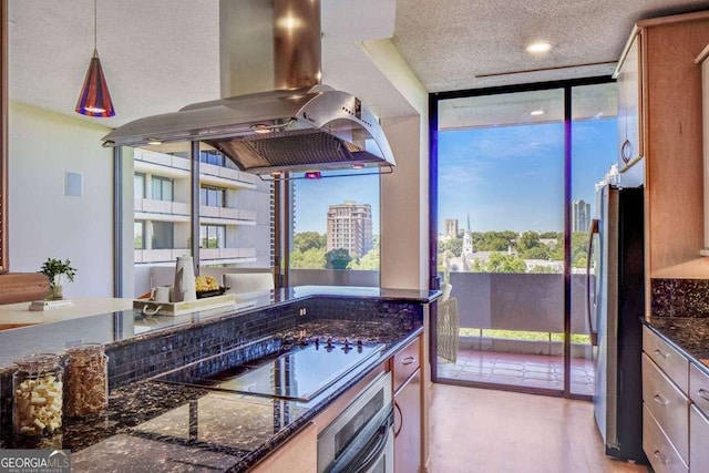 2575 Peachtree Rd NE Unit 15G, Atlanta, GA 30305 - kitchen with island range hood, wall oven, black electric cooktop, dark stone countertops, and freestanding refrigerator