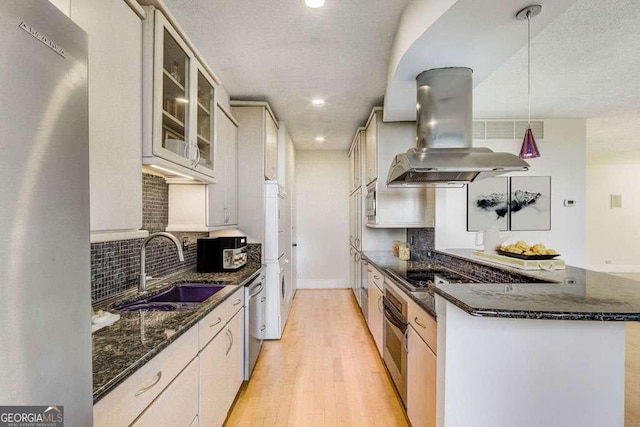 2575 Peachtree Rd NE Unit 15G, Atlanta, GA 30305 - kitchen featuring stainless steel appliances, island exhaust hood, light wood-style flooring, glass insert cabinets, and decorative backsplash