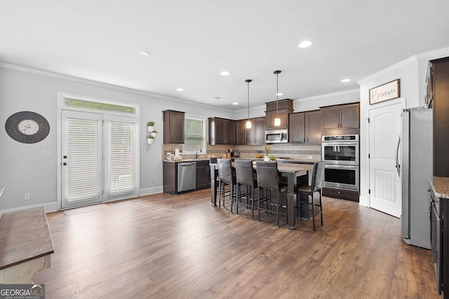 2767 NW Magnolia Creek Dr, Kennesaw, GA 30152 - kitchen featuring stainless steel appliances, ornamental molding, dark brown cabinetry, a kitchen island, and decorative backsplash