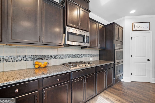 2767 NW Magnolia Creek Dr, Kennesaw, GA 30152 - kitchen with appliances with stainless steel finishes, ornamental molding, dark wood-style flooring, light stone countertops, and dark brown cabinetry