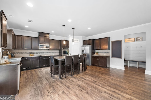 2767 NW Magnolia Creek Dr, Kennesaw, GA 30152 - kitchen featuring stainless steel appliances, crown molding, dark brown cabinets, a breakfast bar area, and decorative backsplash