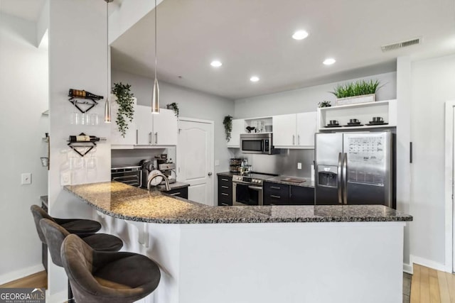 390 17th St NW Unit 6055, Atlanta, GA 30363 - kitchen with appliances with stainless steel finishes, open shelves, a peninsula, dark stone counters, and wood finished floors