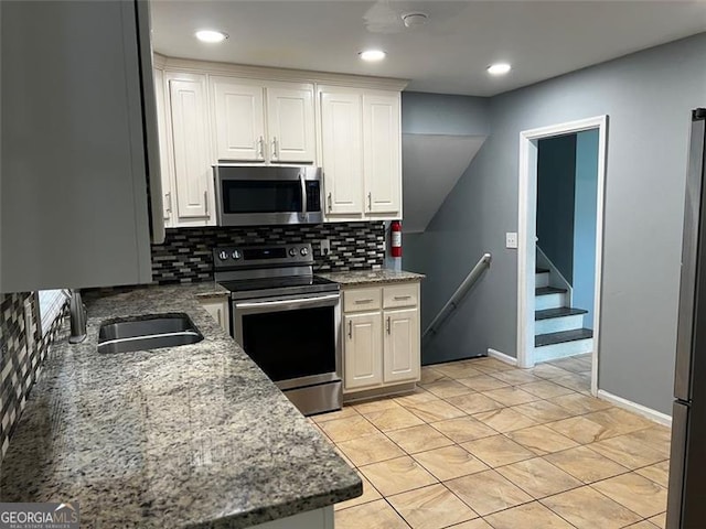 2436 Glenrock Dr, Decatur, GA 30032 - kitchen with appliances with stainless steel finishes, decorative backsplash, white cabinetry, light stone counters, and recessed lighting