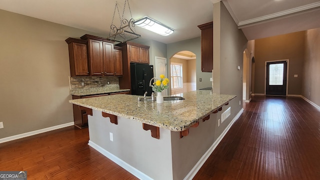 488 Morris Rd, Hiram, GA 30141 - kitchen featuring black fridge with ice dispenser, arched walkways, light stone countertops, a kitchen bar, and a peninsula