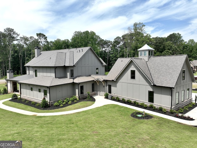 1005 Haddie Way, Alpharetta, GA 30004 - modern farmhouse style home with board and batten siding, a chimney, a front yard, a shingled roof, and view of wooded area