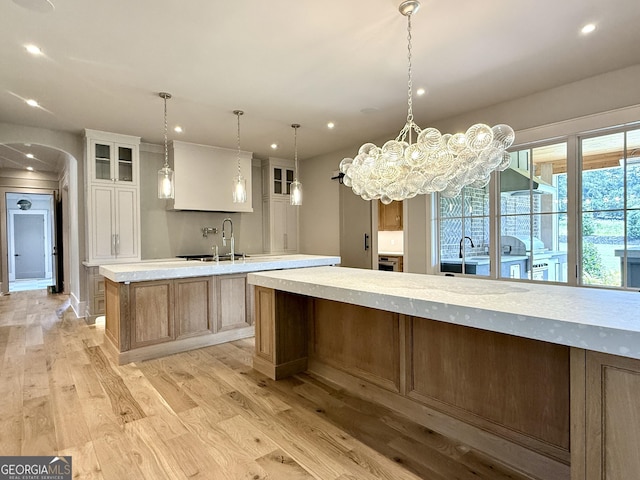1005 Haddie Way, Alpharetta, GA 30004 - kitchen with a large island, light wood-style floors, arched walkways, recessed lighting, and light countertops