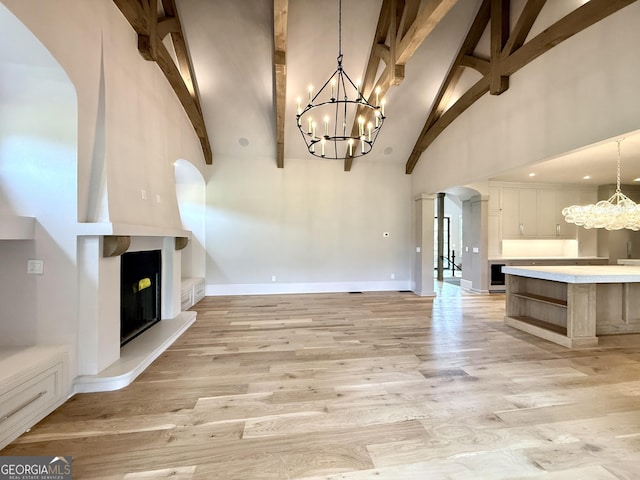 1005 Haddie Way, Alpharetta, GA 30004 - unfurnished living room with a chandelier, arched walkways, high vaulted ceiling, beam ceiling, and a large fireplace