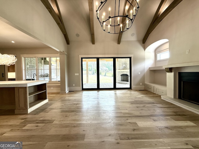 1005 Haddie Way, Alpharetta, GA 30004 - unfurnished living room with a chandelier, a fireplace with raised hearth, high vaulted ceiling, beamed ceiling, and light wood-type flooring