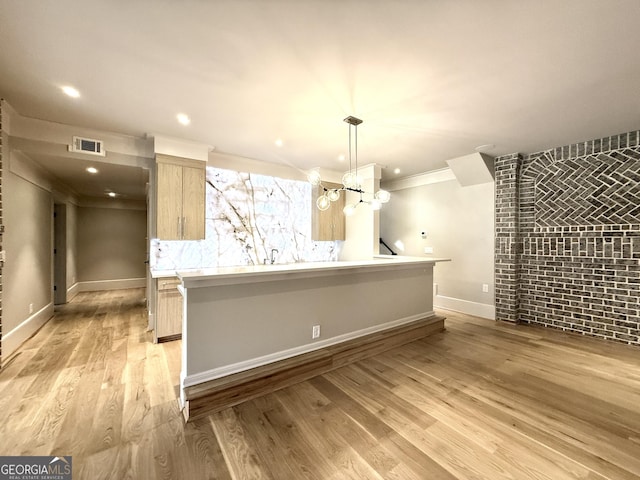 1005 Haddie Way, Alpharetta, GA 30004 - kitchen featuring light wood-style floors, light countertops, light brown cabinets, hanging light fixtures, and ornamental molding