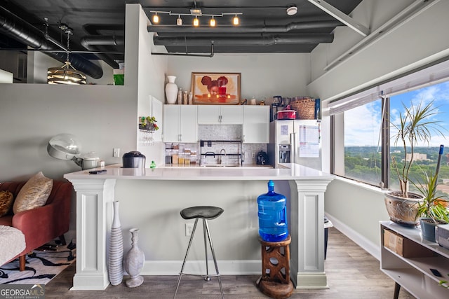 120 Ralph Mcgill Blvd NE Apt 1409, Atlanta, GA 30308 - kitchen with stainless steel fridge with ice dispenser, decorative backsplash, wood finished floors, white cabinets, and a kitchen breakfast bar