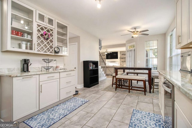2275 Holly Run Dr, Jonesboro, GA 30236 - kitchen with a ceiling fan, white cabinetry, light stone countertops, glass insert cabinets, and dishwasher
