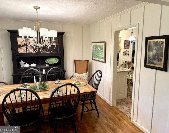 1055 E Hermitage Rd NE, Rome, GA 30161 - dining space with a decorative wall, wood finished floors, a chandelier, a textured ceiling, and ornamental molding