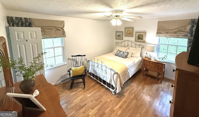 1055 E Hermitage Rd NE, Rome, GA 30161 - bedroom featuring multiple windows, light wood-type flooring, a textured ceiling, and ceiling fan
