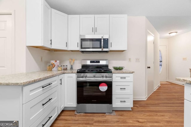 4818 Terrace Green Trce, Stone Mountain, GA 30088 - kitchen with appliances with stainless steel finishes, white cabinetry, light wood-type flooring, and light stone countertops