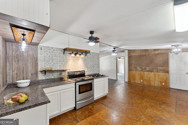 99 Conifer Dr, Guyton, GA 31312 - kitchen with stainless steel appliances, wood walls, dark countertops, ceiling fan, and white cabinetry