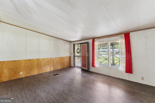 99 Conifer Dr, Guyton, GA 31312 - empty room featuring wood finished floors, a textured ceiling, wood walls, and lofted ceiling