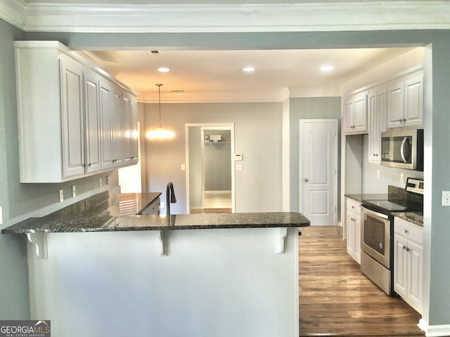 1433 Cotton Trl SW, Conyers, GA 30094 - kitchen featuring appliances with stainless steel finishes, a peninsula, a kitchen bar, wood finished floors, and ornamental molding