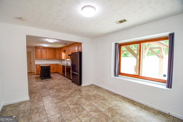 125 Point View Ct, Tyrone, GA 30290 - kitchen featuring freestanding refrigerator, light countertops, a textured ceiling, and brown cabinets