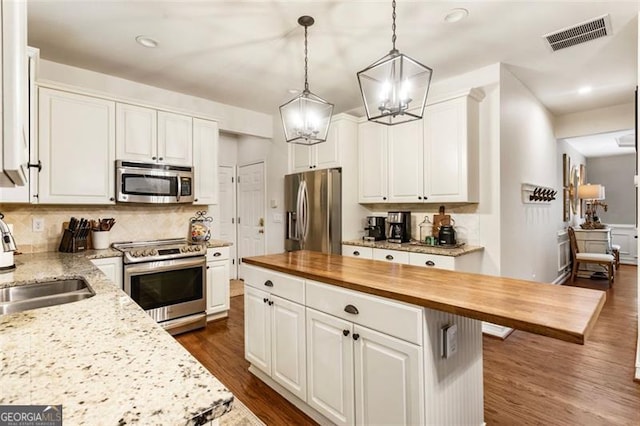 4401 Madison Woods Dr NW Unit 4401, Marietta, GA 30064 - kitchen featuring stainless steel appliances, wood counters, a chandelier, white cabinetry, and backsplash