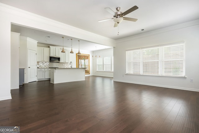 4583 Grenadine Cir, Acworth, GA 30101 - unfurnished living room featuring crown molding, ceiling fan, a chandelier, and dark wood finished floors
