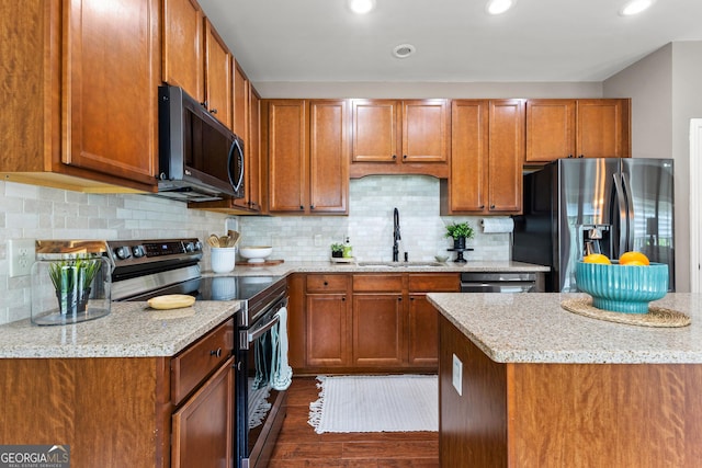 51 Stonebridge Way, Newnan, GA 30265 - kitchen featuring appliances with stainless steel finishes, brown cabinets, dark wood finished floors, light stone counters, and recessed lighting