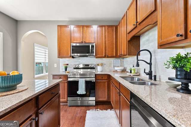 51 Stonebridge Way, Newnan, GA 30265 - kitchen featuring stainless steel appliances, light stone countertops, dark wood-style flooring, and brown cabinetry
