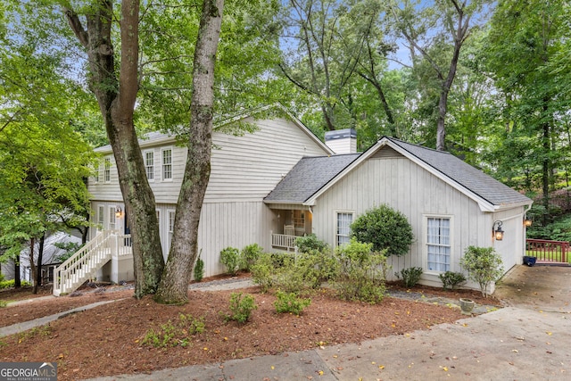 2240 Six Branches Dr, Roswell, GA 30076 - view of front facade featuring a chimney, a shingled roof, view of scattered trees, and stairs