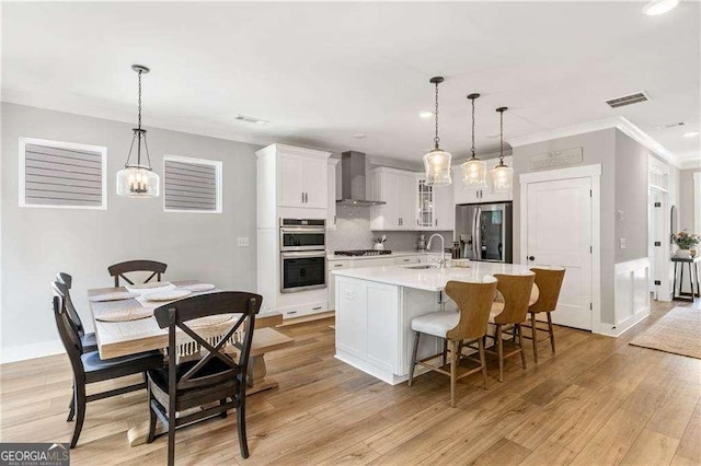 338 Boundless Ln, Canton, GA 30114 - kitchen with wall chimney exhaust hood, stainless steel appliances, white cabinets, a breakfast bar area, and glass insert cabinets