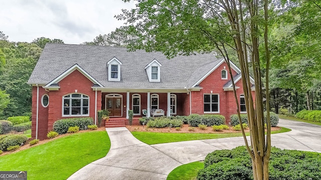 750 Old Loganville Rd SW, Loganville, GA 30052 - cape cod-style house featuring a porch, brick siding, a front yard, and roof with shingles