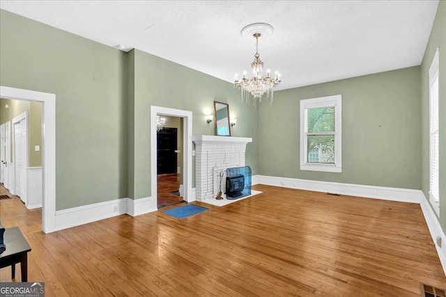 226 Noyes St, Cedartown, GA 30125 - unfurnished living room with wood-type flooring, a chandelier, and a brick fireplace