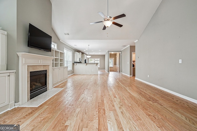6722 Blue Heron Way, Flowery Branch, GA 30542 - unfurnished living room featuring a ceiling fan, a tiled fireplace, light wood-style flooring, and high vaulted ceiling
