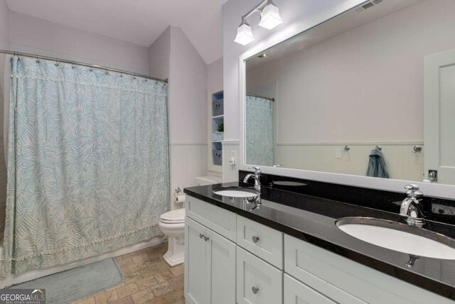 2375 Hyde Park Ct NW, Atlanta, GA 30318 - bathroom with stone tile flooring, double vanity, shower / bath combo with shower curtain, and wainscoting
