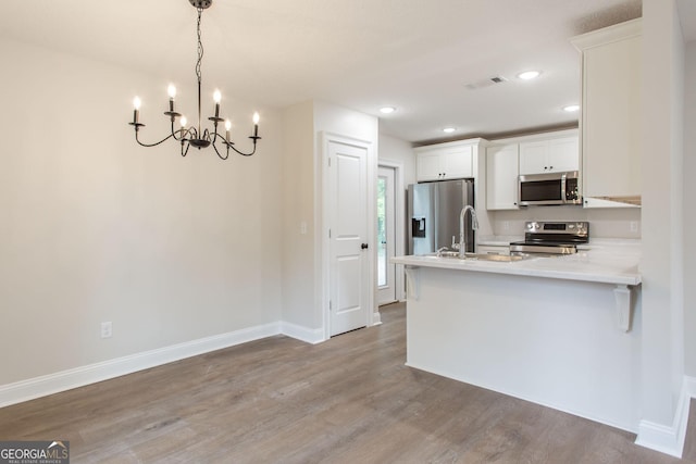 1920 Darling Ave, Waycross, GA 31501 - kitchen featuring stainless steel appliances, a chandelier, wood finished floors, light countertops, and white cabinetry