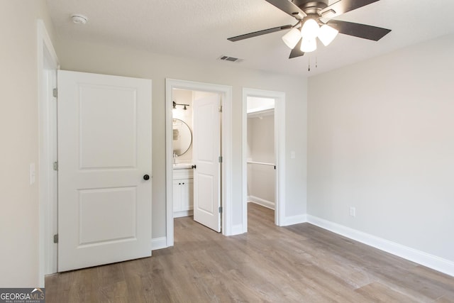 1920 Darling Ave, Waycross, GA 31501 - unfurnished bedroom with a spacious closet, wood finished floors, a closet, ceiling fan, and connected bathroom