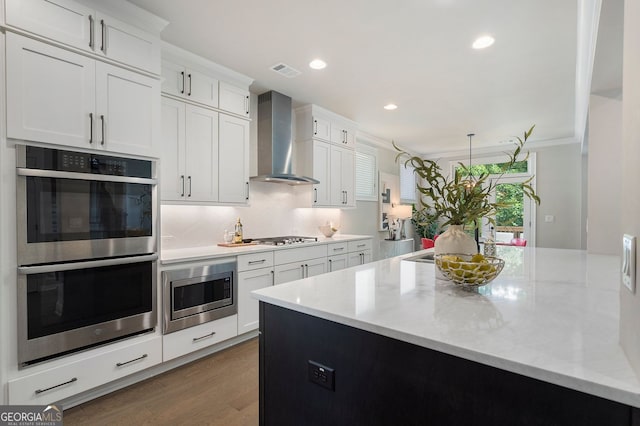 510 Walden Glen Ln, Alpharetta, GA 30004 - kitchen with appliances with stainless steel finishes, wall chimney exhaust hood, white cabinets, wood finished floors, and light stone counters