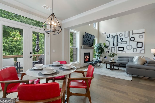 510 Walden Glen Ln, Alpharetta, GA 30004 - dining space with healthy amount of natural light, a chandelier, a lit fireplace, wood finished floors, and ornamental molding