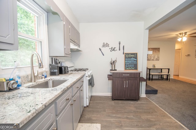 109 Susie Pl, Newnan, GA 30265 - kitchen featuring white range with gas cooktop, under cabinet range hood, light stone counters, wood finished floors, and ceiling fan