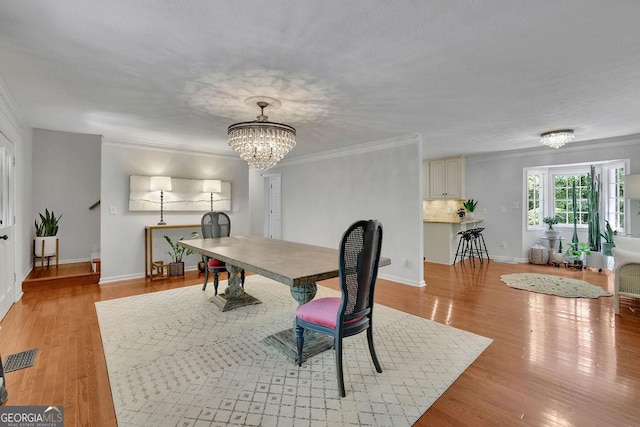 2095 Honeysuckle Dr, Cumming, GA 30040 - dining room with a chandelier, light wood-type flooring, and crown molding