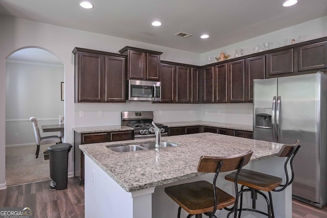 110 Serendipity Way, Dallas, GA 30157 - kitchen featuring stainless steel appliances, arched walkways, dark wood-type flooring, dark brown cabinets, and light stone counters