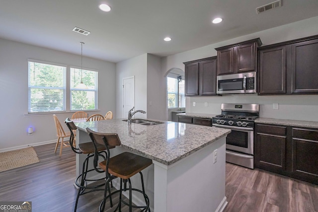 110 Serendipity Way, Dallas, GA 30157 - kitchen featuring appliances with stainless steel finishes, arched walkways, an island with sink, light stone countertops, and dark brown cabinetry