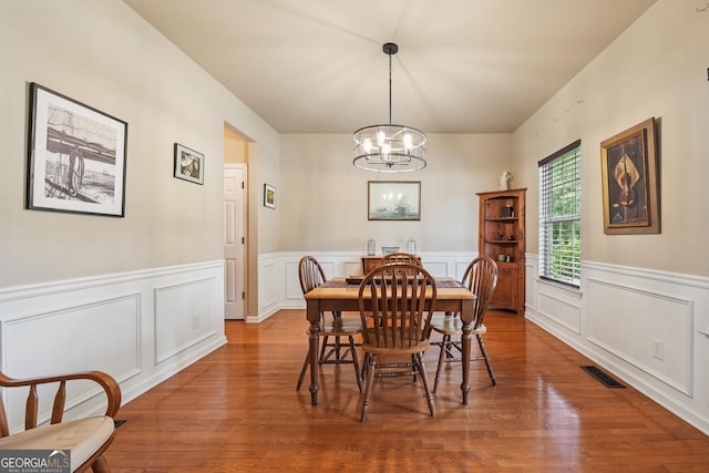 6521 Boulder Crest Ct, Flowery Branch, GA 30542 - dining area with a chandelier, wood finished floors, a decorative wall, and a wainscoted wall