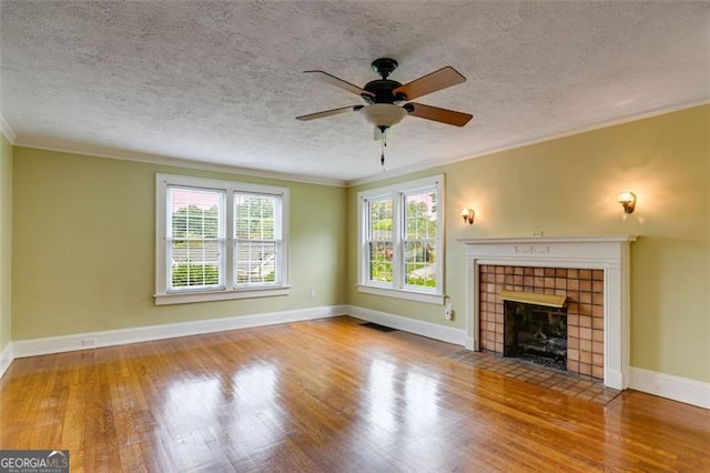 303 Hardee St, Dallas, GA 30132 - unfurnished living room with wood finished floors, ceiling fan, a tile fireplace, a textured ceiling, and crown molding
