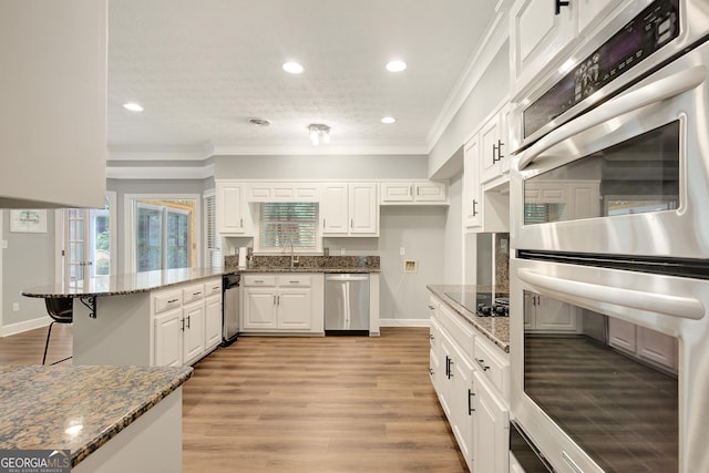 40 Springwater Chase, Newnan, GA 30265 - kitchen featuring stainless steel appliances, a peninsula, ornamental molding, white cabinets, and dark stone counters