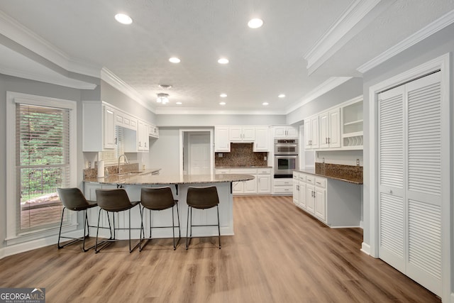 40 Springwater Chase, Newnan, GA 30265 - kitchen featuring a peninsula, a breakfast bar area, light stone countertops, white cabinetry, and open shelves