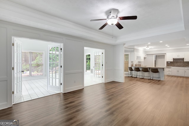 40 Springwater Chase, Newnan, GA 30265 - unfurnished living room featuring crown molding, wood finished floors, a ceiling fan, a decorative wall, and a tray ceiling