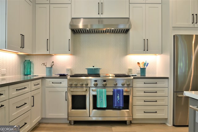 1330 Jackson Ridge Rd, Greensboro, GA 30642 - kitchen with stainless steel appliances, wall chimney range hood, light wood-style flooring, backsplash, and dark countertops