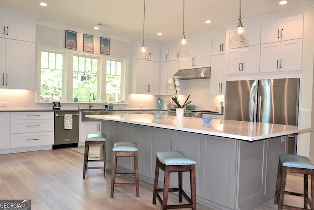 1330 Jackson Ridge Rd, Greensboro, GA 30642 - kitchen featuring appliances with stainless steel finishes, under cabinet range hood, white cabinets, crown molding, and a breakfast bar