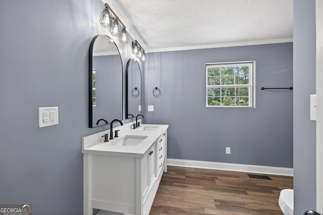 106 Oak Ln, Eatonton, GA 31024 - bathroom featuring wood finished floors, ornamental molding, a textured ceiling, and double vanity