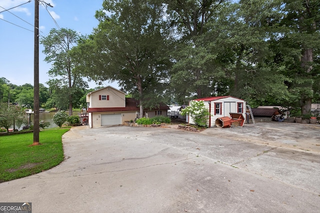 106 Oak Ln, Eatonton, GA 31024 - view of front facade with concrete driveway, a garage, a storage unit, and a front lawn