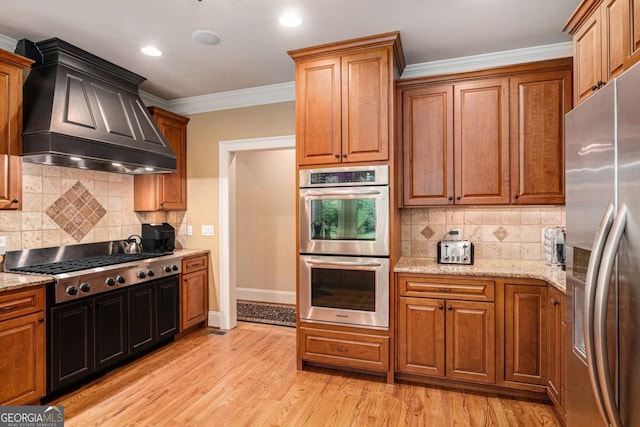 287 Scenic Falls Blvd, Hoschton, GA 30548 - kitchen with appliances with stainless steel finishes, custom range hood, light wood-style floors, ornamental molding, and decorative backsplash